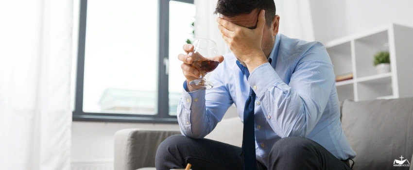 HHRC-A sad man sitting on a couch, holding an alcoholic drink